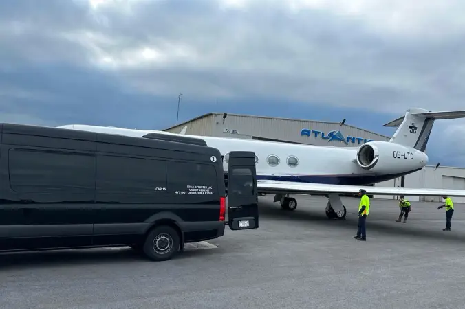 Sprinter van with open doors next to a private jet at the airport